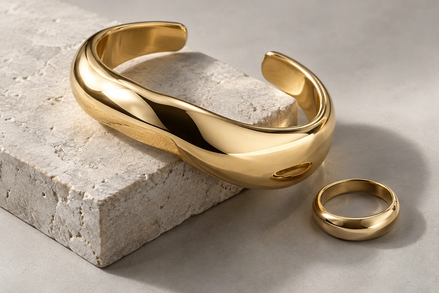Sculptural gold cuff and ring on pale limestone